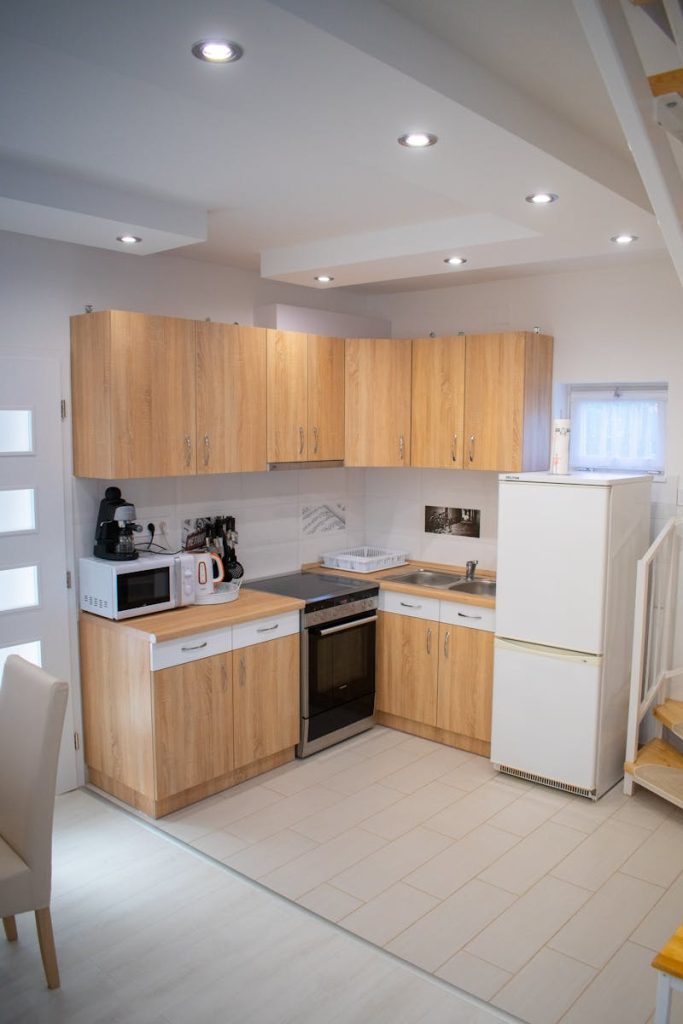A compact contemporary kitchen featuring wooden cabinets and modern appliances.
